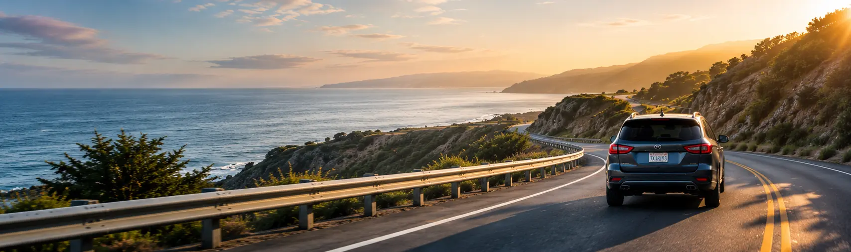 Car driving along a scenic coastal highway at sunset