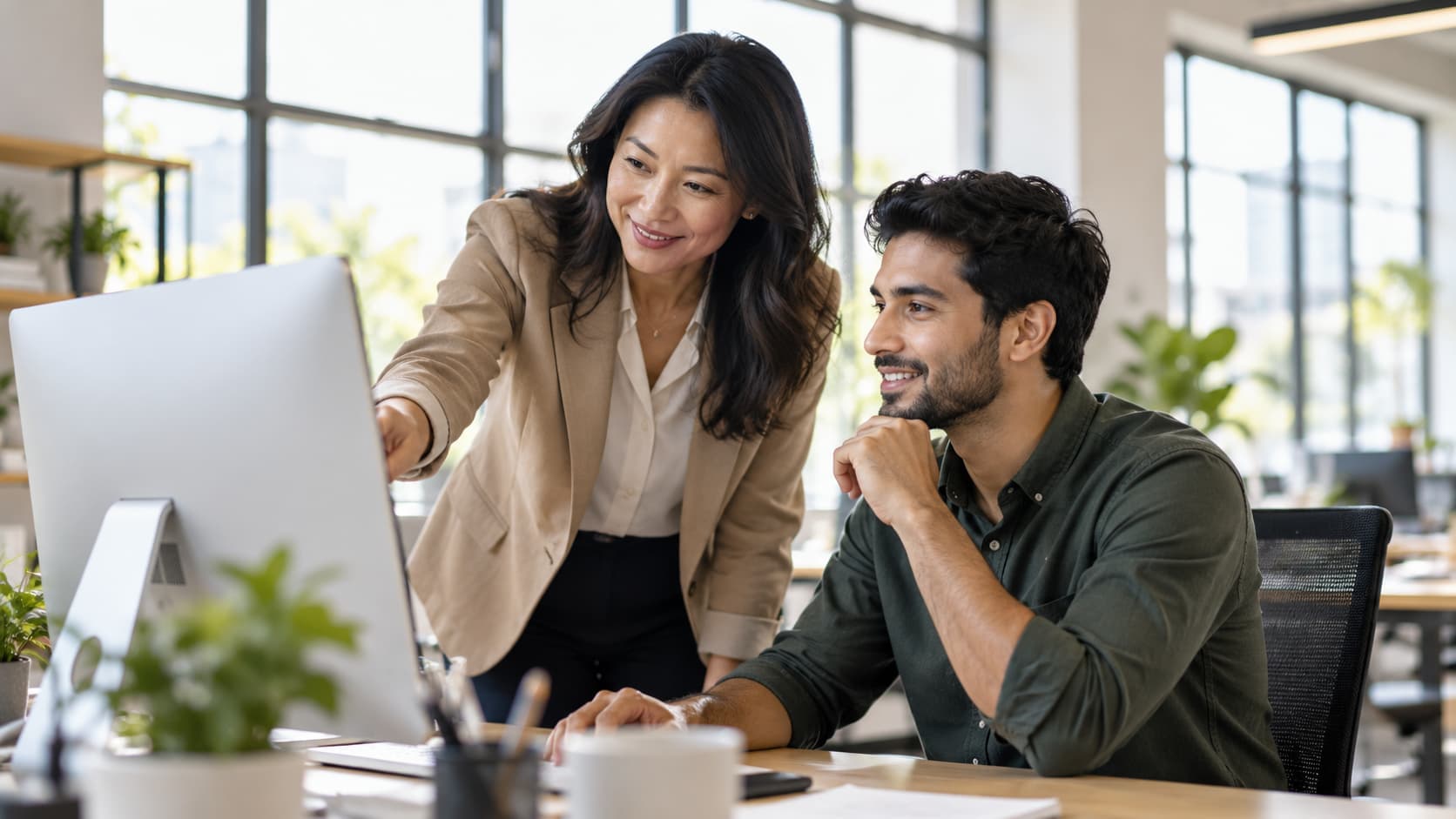 Manager guiding an employee through a task on a computer, demonstrating leadership, workplace accountability, and clear expectations.